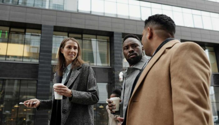 A group of diverse professionals discussing business during a coffee break outdoors.