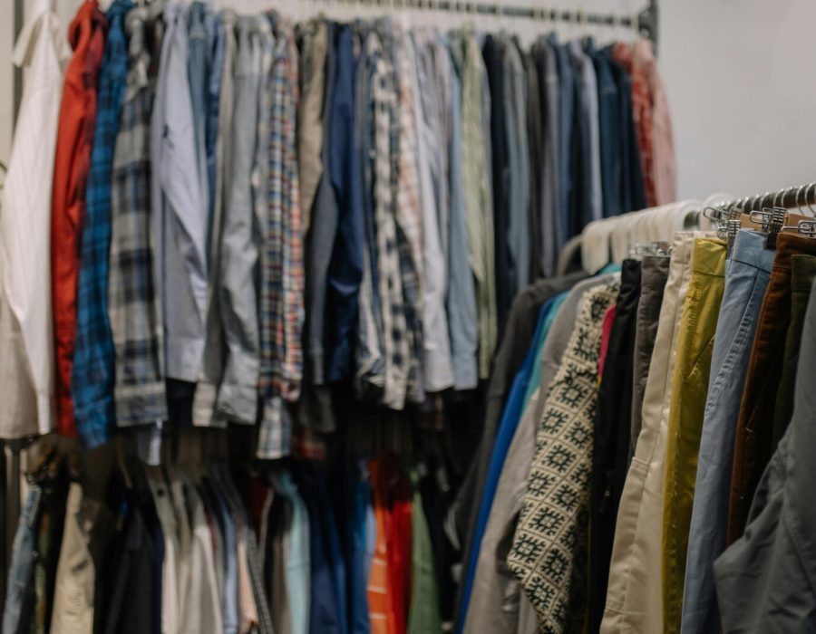 Assorted clothing on racks in a thrift shop, showcasing various styles and colors.