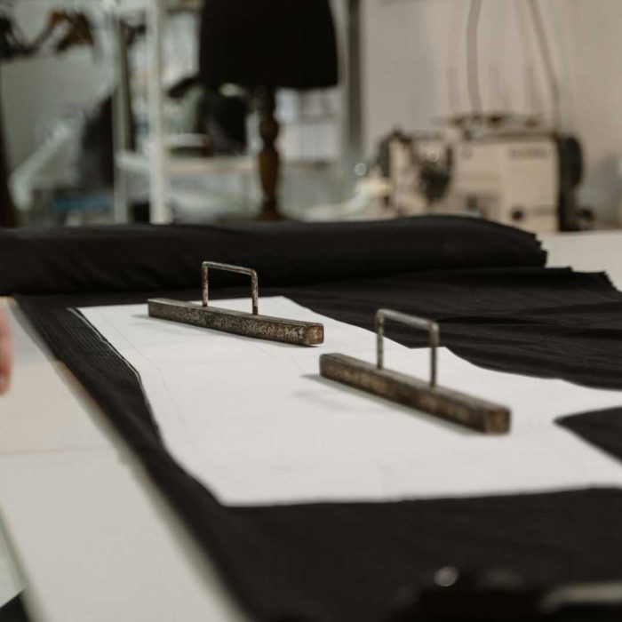 Close-up of a tailor measuring fabric with a tape in a sewing studio.