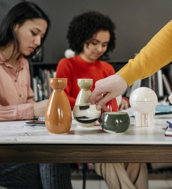 Women collaborating in a stylish office with ceramics and notes on the desk.