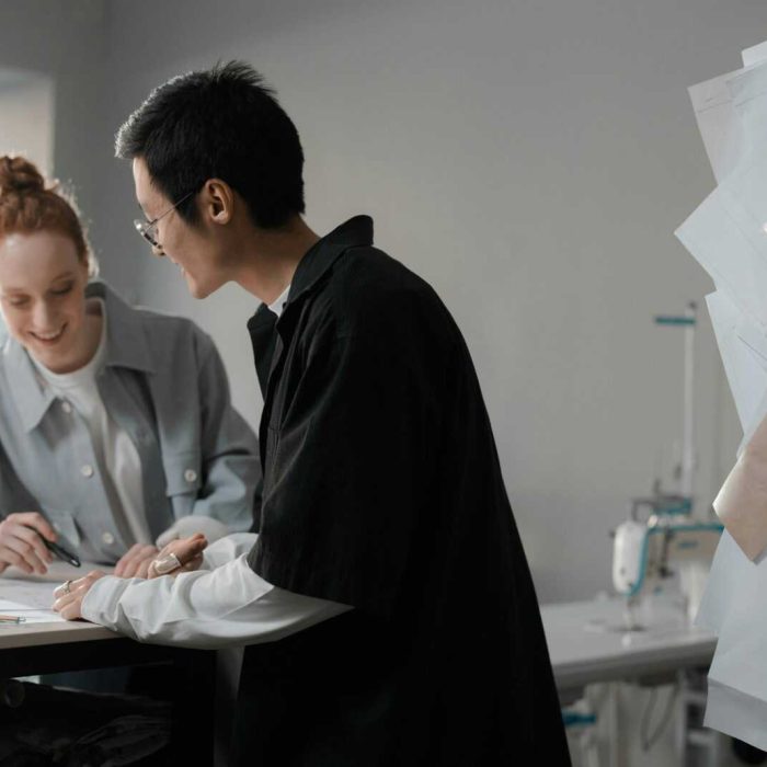 Two diverse fashion designers brainstorming at a workspace, focused on creative planning.